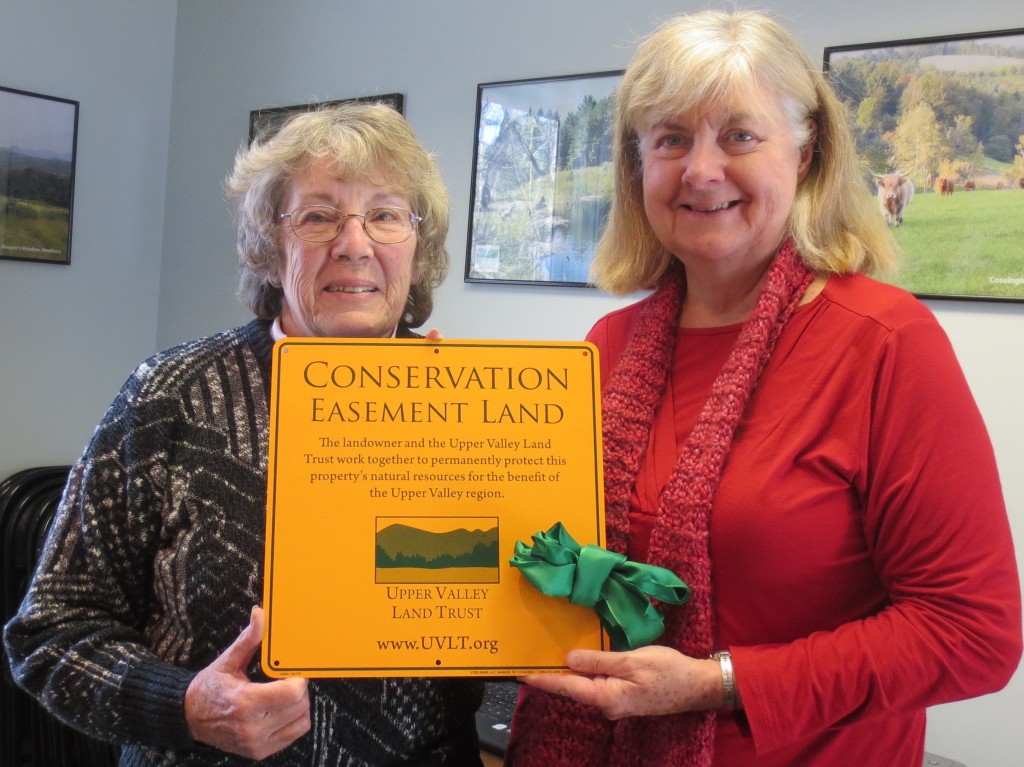 Lora Chatfield (right) and Nancy Jones hold a conserved land sign that will mark Helen's Haven.